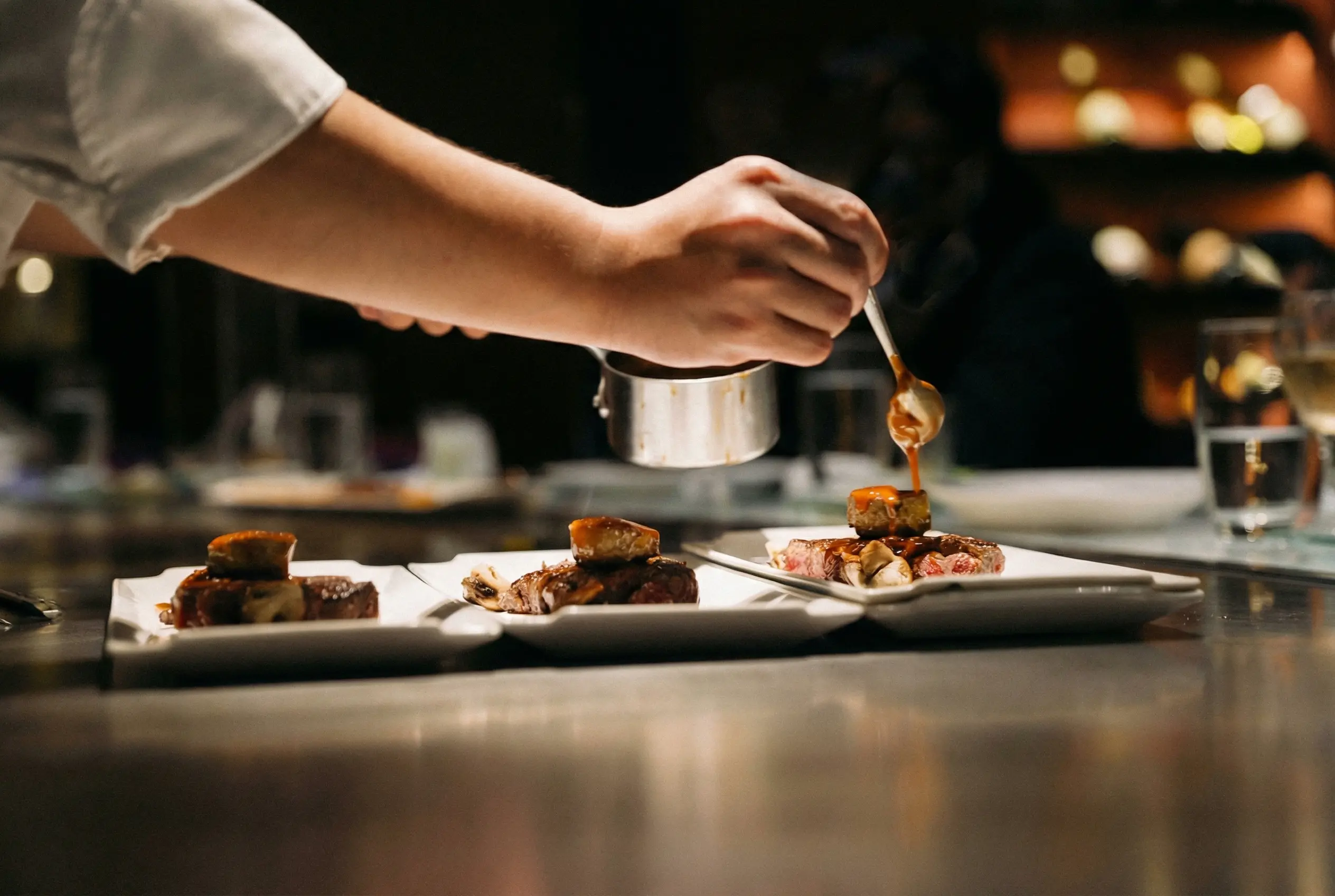 Detail of a chef plating a fine-dining dish, evoking the care and precision of the Vosvil experience.